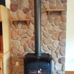 Gas powered fireplace in corner with rock background close up