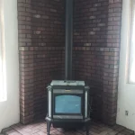 wood burning fireplace in corner lined with dark red brick close up